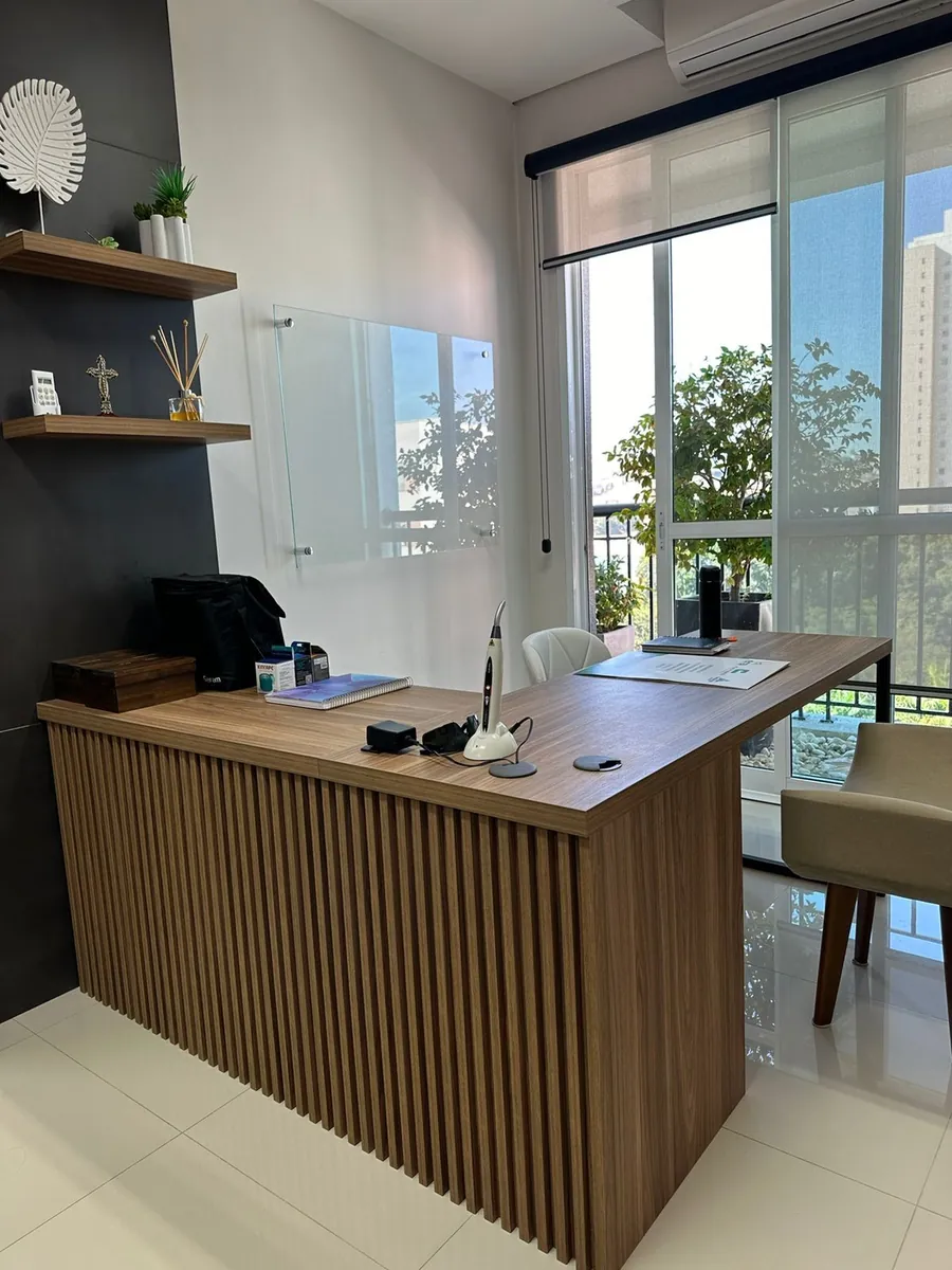 Mesa de atendimento do consultório, ao lado da janela
